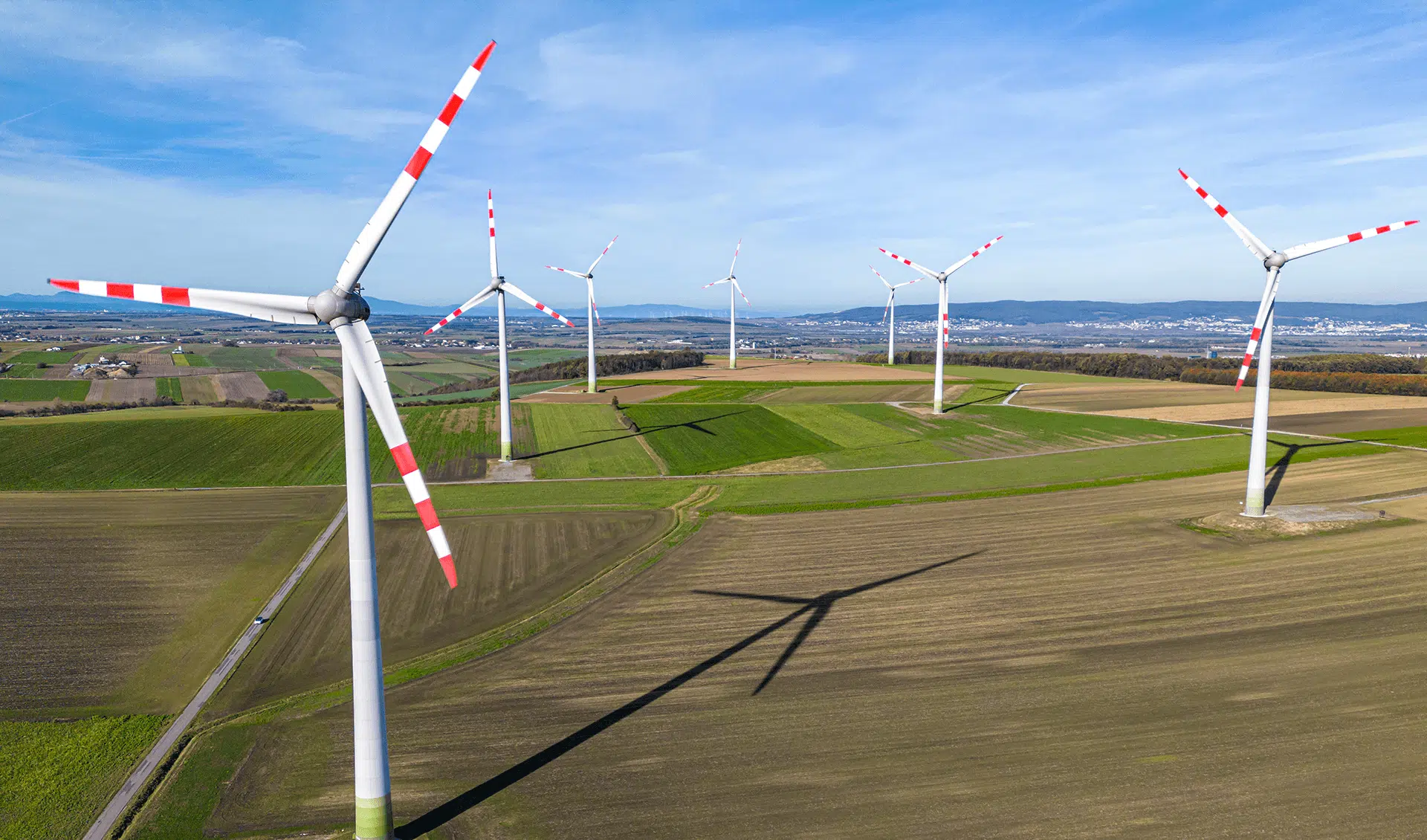 Windräder in Niederösterreich mit roten Streifen auf den Rotorblättern, im Hintergrund eine Stadt